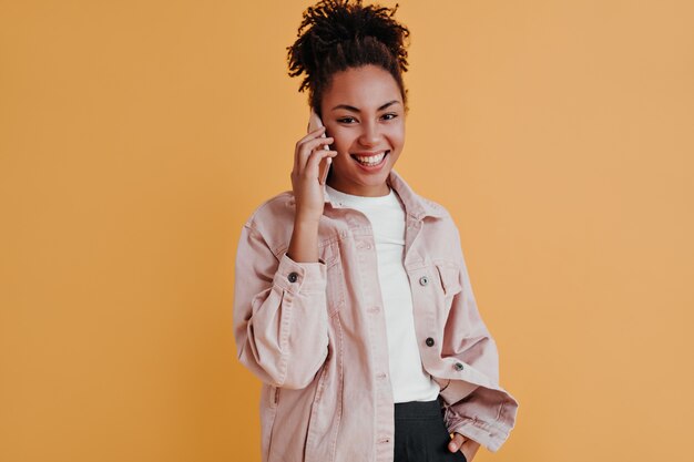 Cheerful woman in jacket talking on smartphone