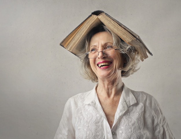 Free Photo cheerful woman, laughing with a book on her head