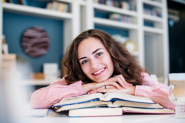 Free photo cheerful woman leaning on books