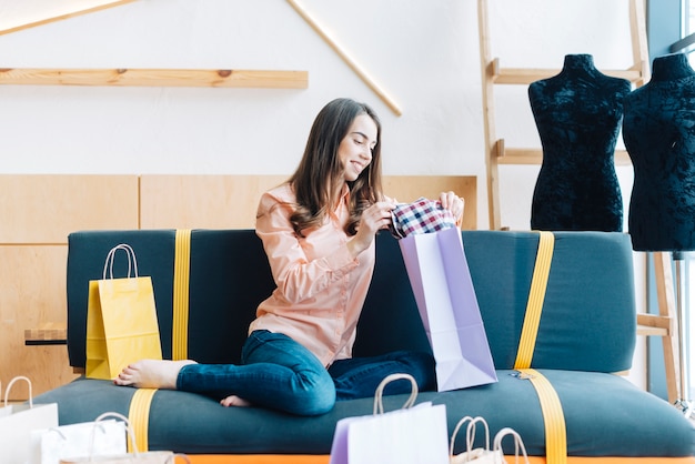 Cheerful woman looking at purchases on sofa