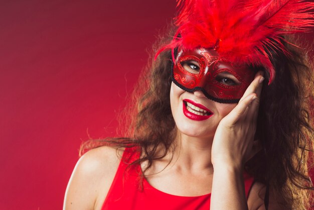 Cheerful woman in red mask with feathers