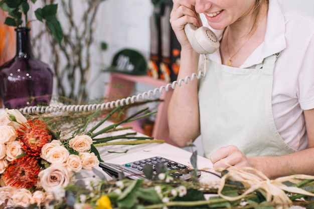 Free photo cheerful woman speaking on phone in shop