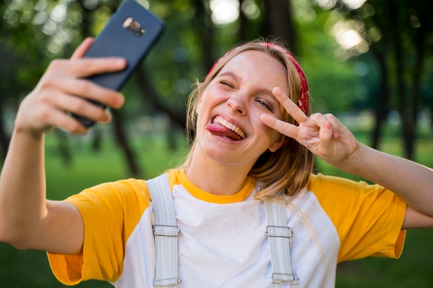 Cheerful woman taking selfie outdoors