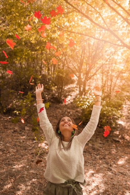 Free photo cheerful woman throwing autumn leaves