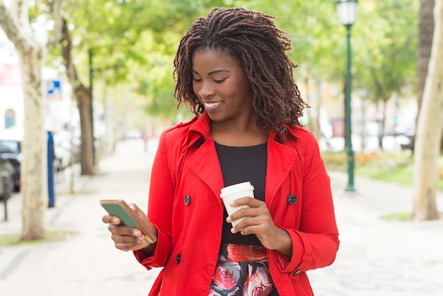 Cheerful woman using smartphone in park