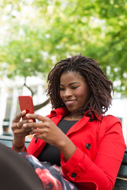 Cheerful woman using smartphone on street