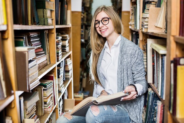 Cheerful woman with book in library