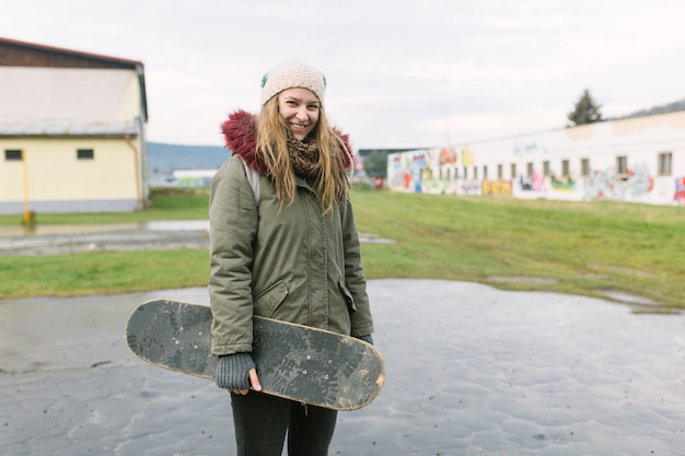 Free photo cheerful woman with skateboard looking at camera