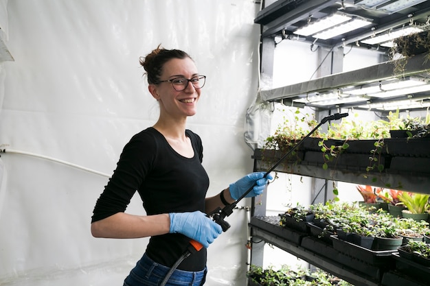 Free photo cheerful woman with sprayer in hothouse