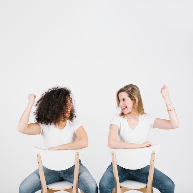 Free photo cheerful women on chairs showing muscles