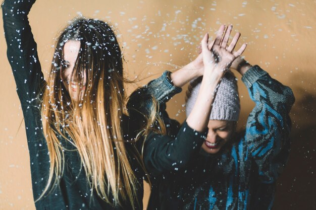 Cheerful women dancing under snow