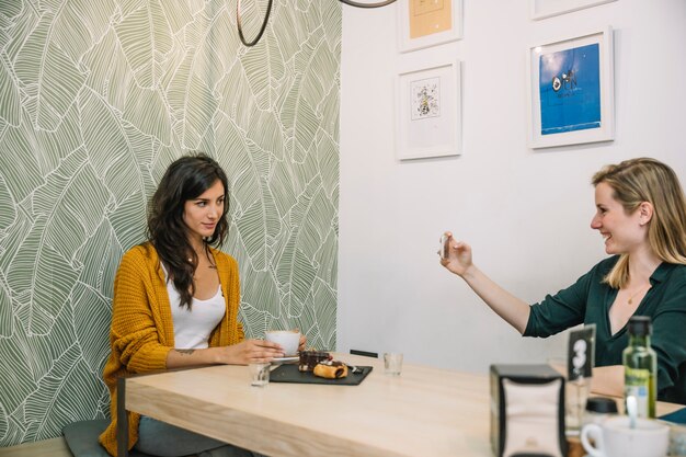 Cheerful women taking pictures in cafe