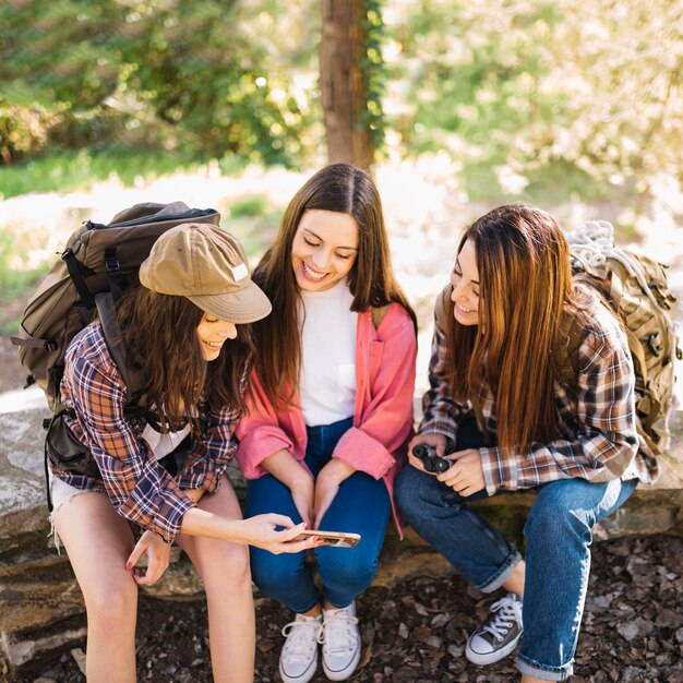 Cheerful women using smartphone on trip