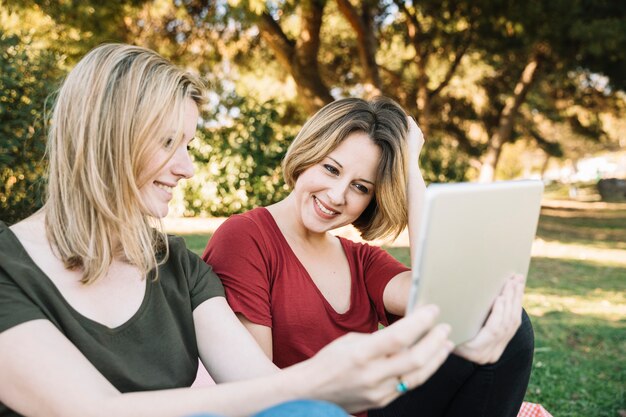 Cheerful women using tablet in park