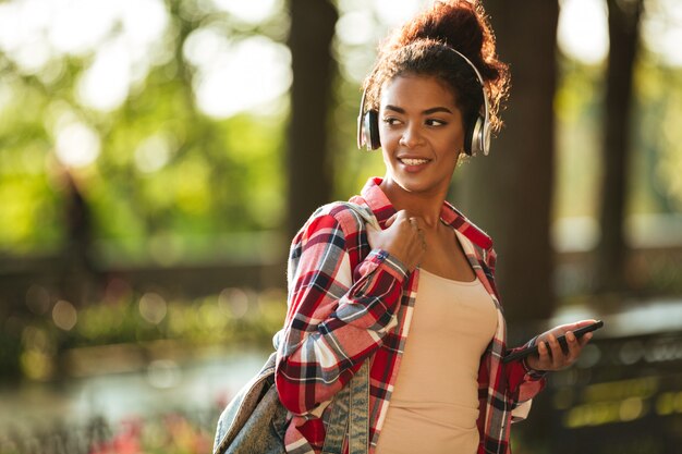 Cheerful young african woman walking outdoors