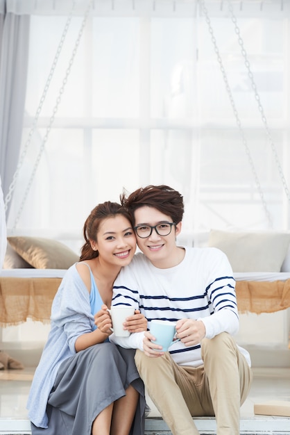 Cheerful young Asian couple enjoying coffee