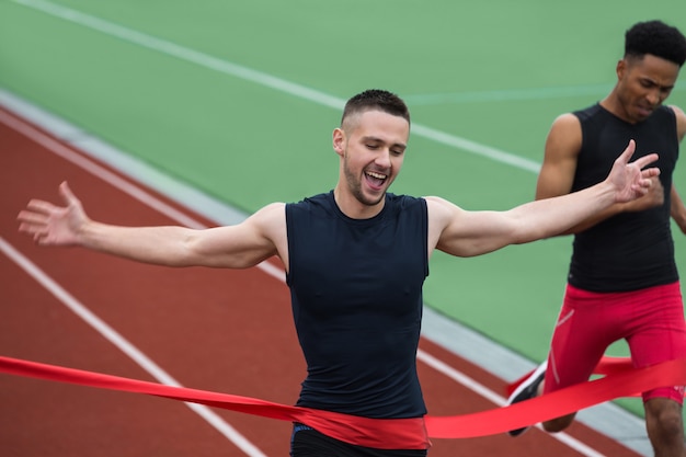 Free photo cheerful young athlete man crossing finish line