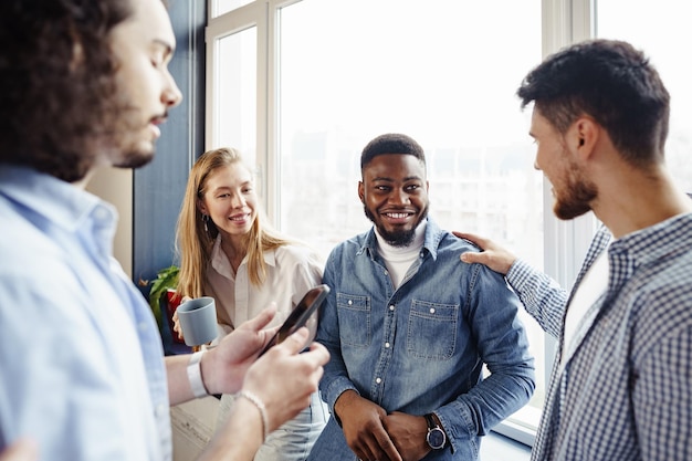 Cheerful young business people have a talk during coffee break in office