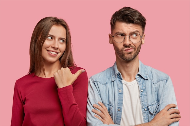 Free photo cheerful young couple posing against the pink wall