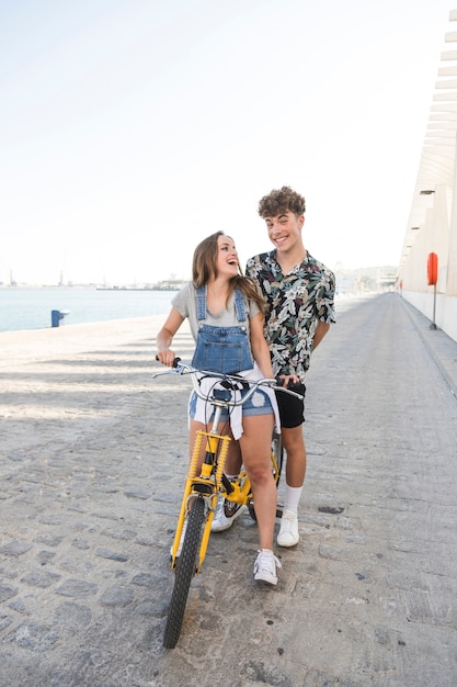 Cheerful young couple with bicycle having fun