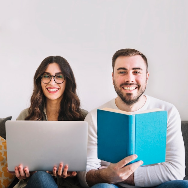 Cheerful young couple with laptop and book