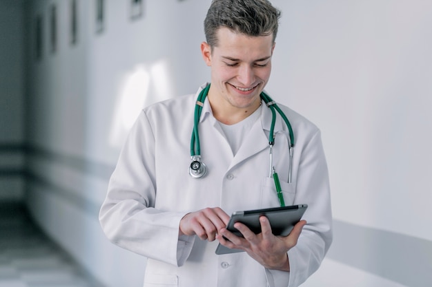 Free photo cheerful young doctor using tablet