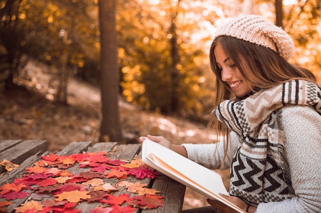 Free Photo cheerful young female reading at table in park