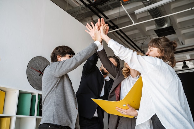 Free Photo cheerful young group of people standing in the office and giving high five