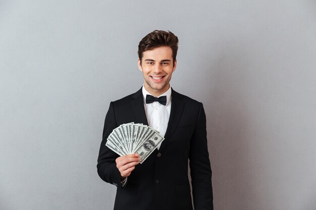 Cheerful young man in official suit holding money.