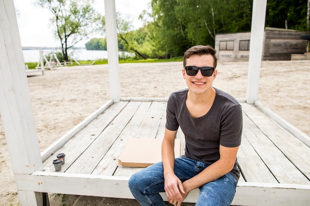 Free Photo cheerful young man sitting on beach