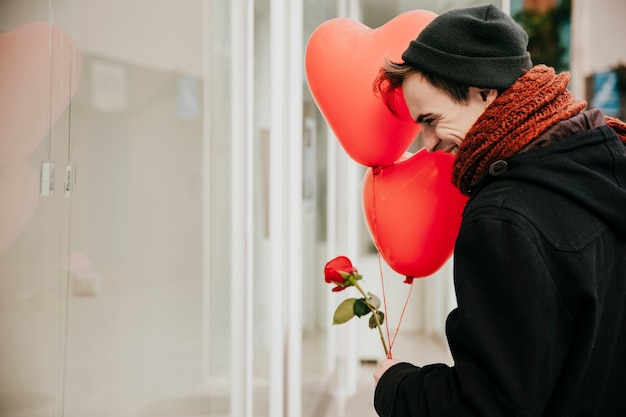 Cheerful young man with balloons on street