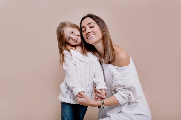 Cheerful young mother looks at the camera, whistles and hugging a daughter