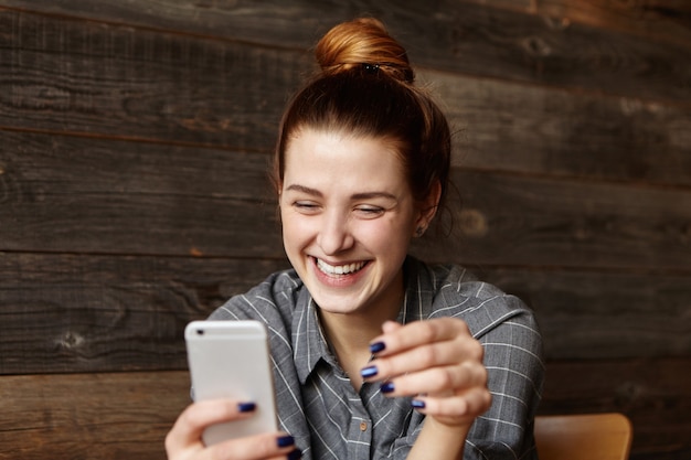 Free photo cheerful young redhead female student with cute smile siting in modern cafe interior