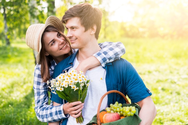 Cheerful young woman embracing lover in park