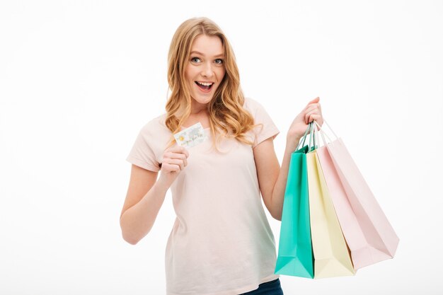 Cheerful young woman holding credit card and shopping bags.