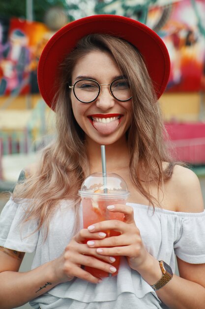 Cheerful young woman holding a drink while smiling