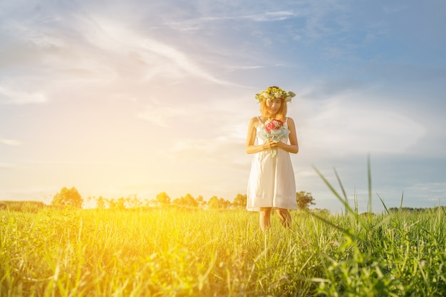 Cheerful young woman holding her bouquet in the meadow