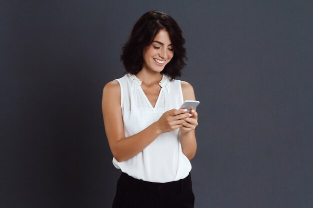 Cheerful young woman holding her phone in hands