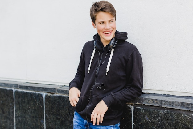 Cheerful youngster leaning on wall