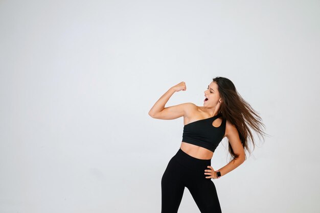 Cheerfully beautiful smiling sporty woman demonstrating biceps