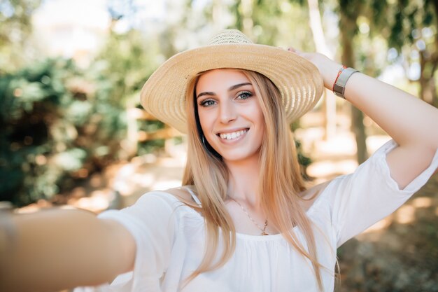 Cheert. Selfie time. Young happy lady in a spring vacation, walking in the city photographing herself on a sunny day