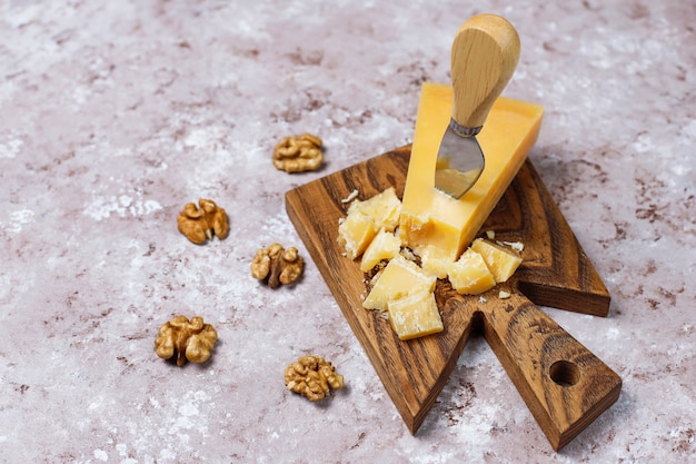 Free photo cheese board with hard cheese ,cheese knife,red wine glass,grape on brown concrete surface