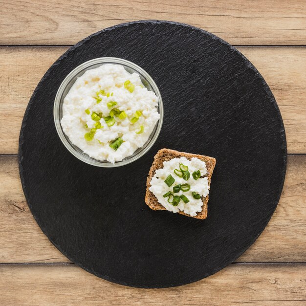 Cheese on brown bread over the black slate serving board on desk