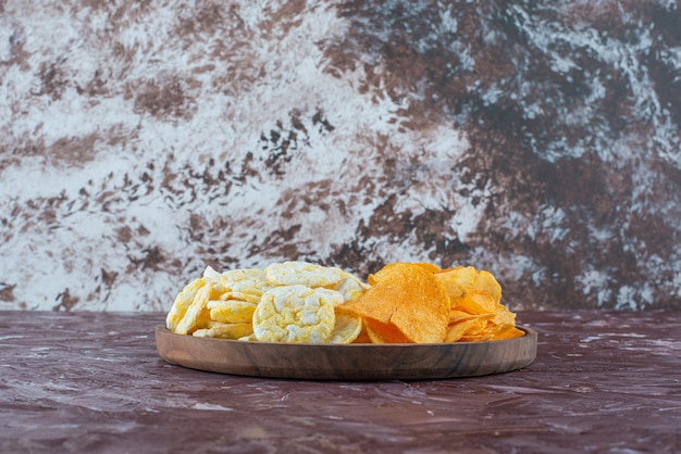 Free photo cheese chips and potato chips in plate, on the marble table.