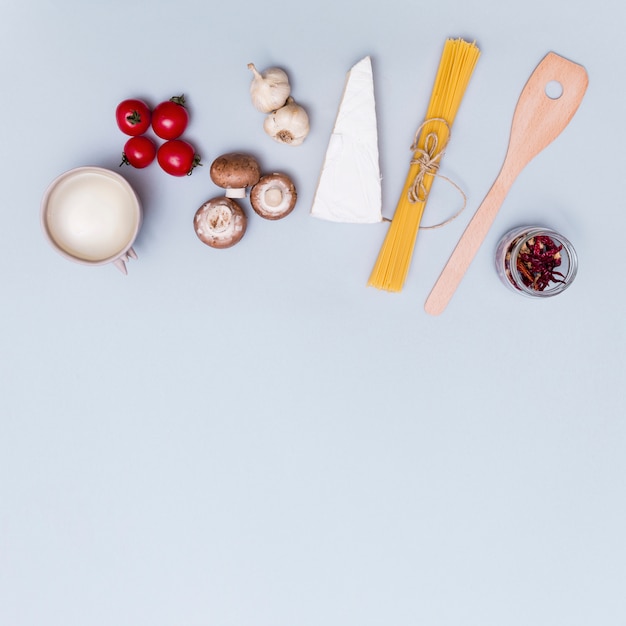 Free photo cheese; fresh vegetables and white sauce for making spaghetti pasta on gray surface