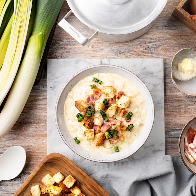 Cheese leek soup with croutons and bacon in a bowl on a wooden table