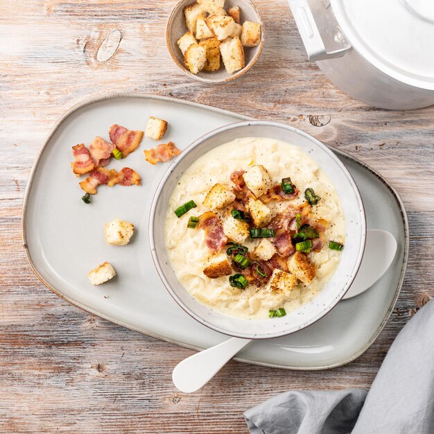 Cheese leek soup with croutons and bacon in a bowl on a wooden table