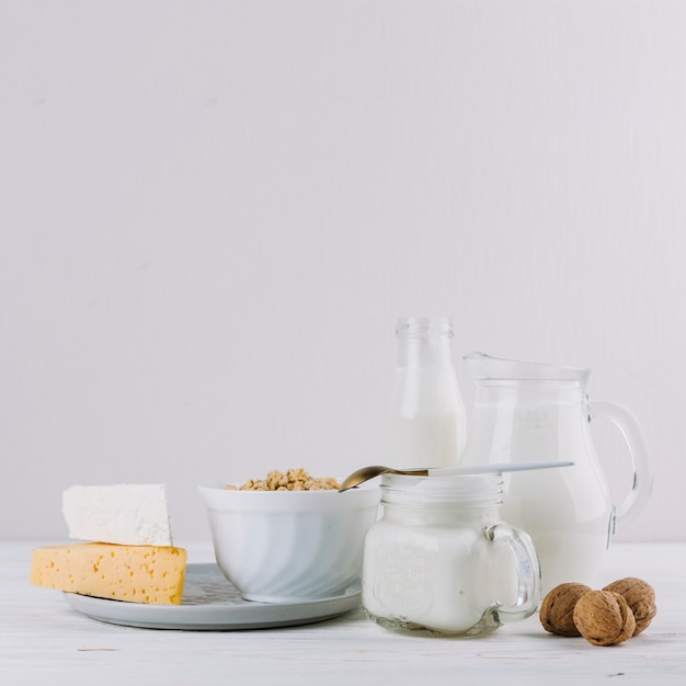 Cheese; milk; bowl of cereals and walnuts over white backdrop