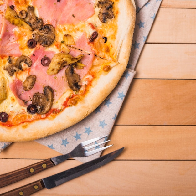 Free photo cheese mushroom pizza on wooden table with fork and knife