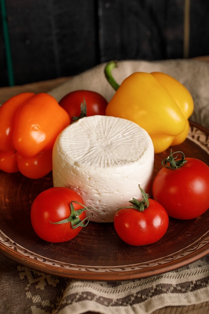 Cheese plate with tomato and peppers on a rustic towel